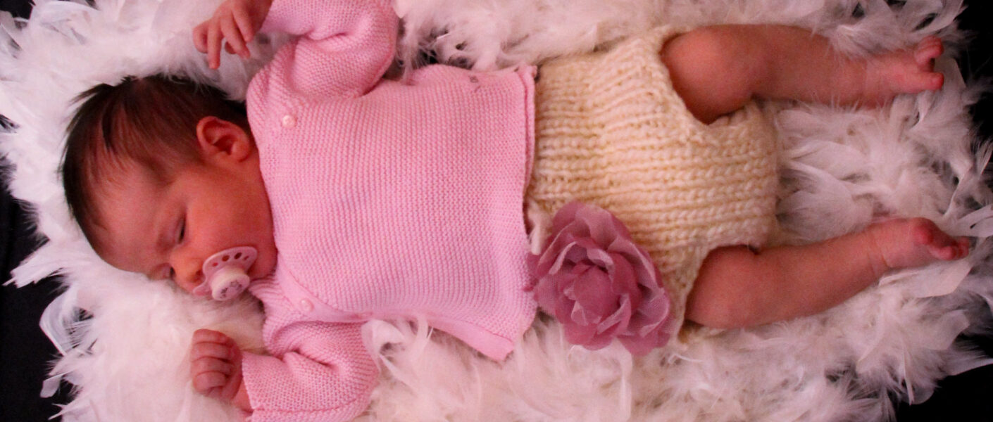 bébé fille sur plumes blanches fleur rose violet